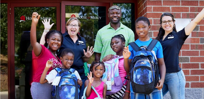 A family shows off new backpacks collected through the House of Mercy school supply drive.