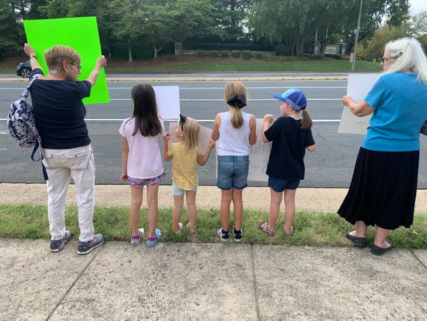 Local family holds signs along Linton Hall Road, Bristow, to protest data centers in neighborhoods. 