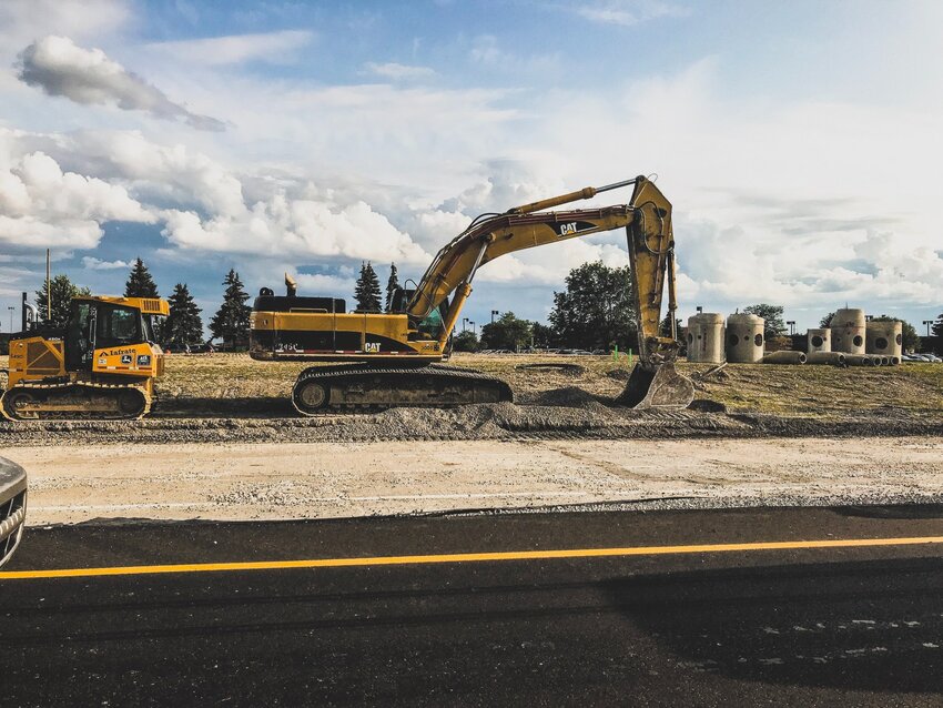 Construction vehicles lay near asphalt along a road. One benefit is asphalt is that it can be recycled and reused.