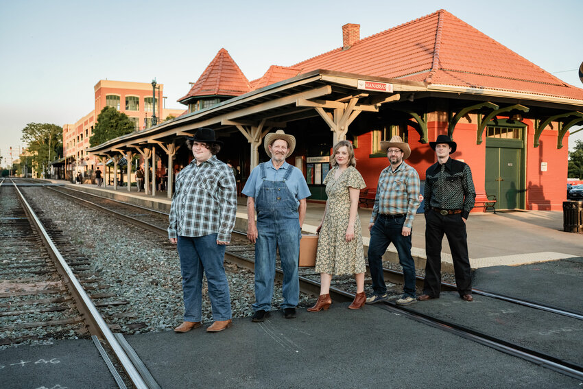Members of the Prince William Little Theatre Cast of '110 in the Shade' act out the train scene in front of Manassas VRE Train Station.