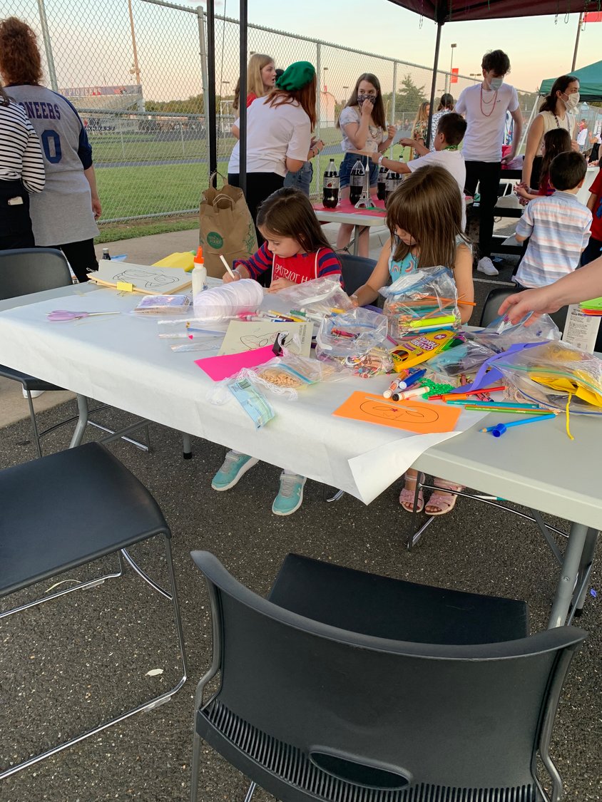 Children create masks at one of the student operated club booths.