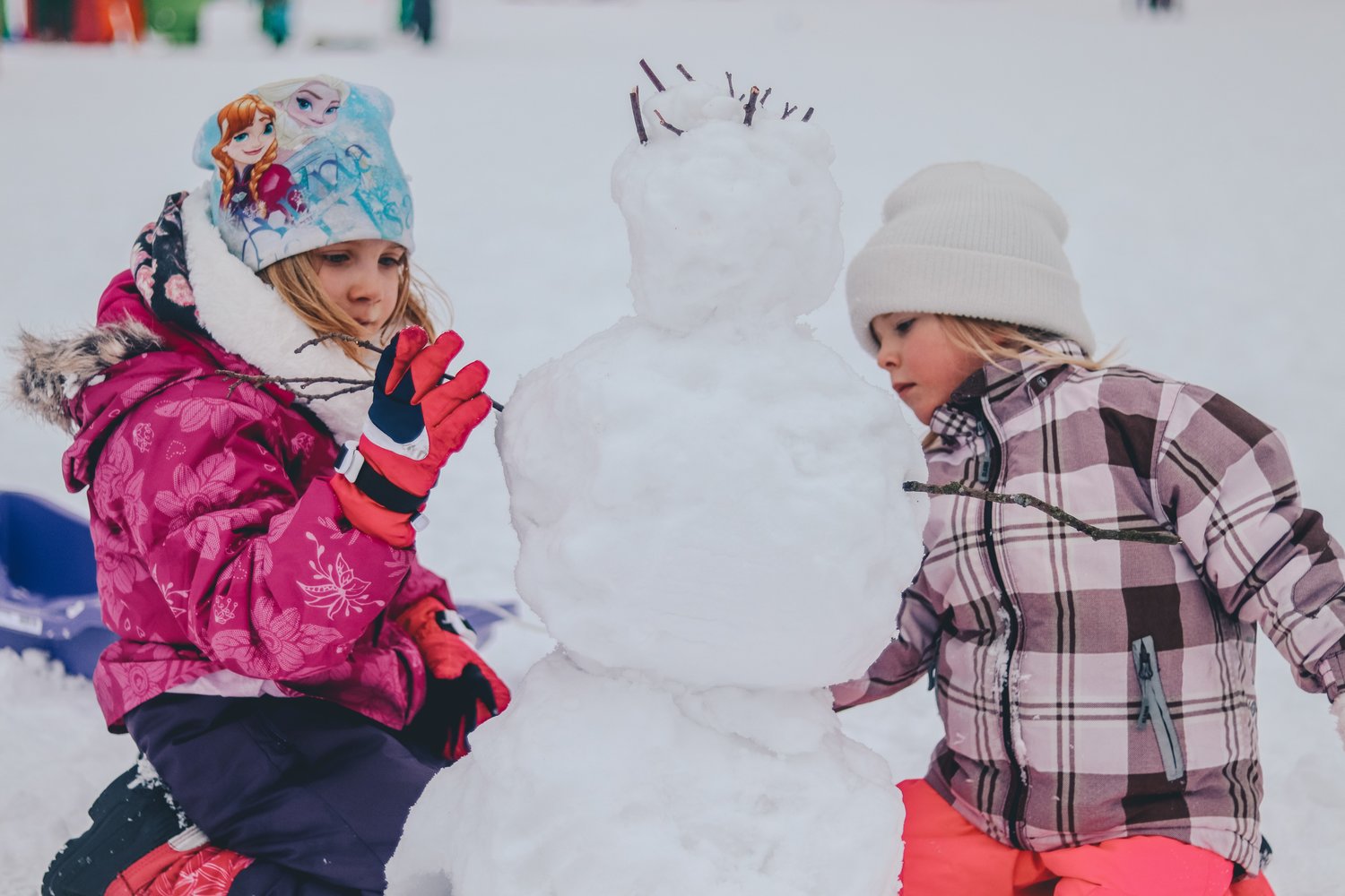 Little girls build snow man.