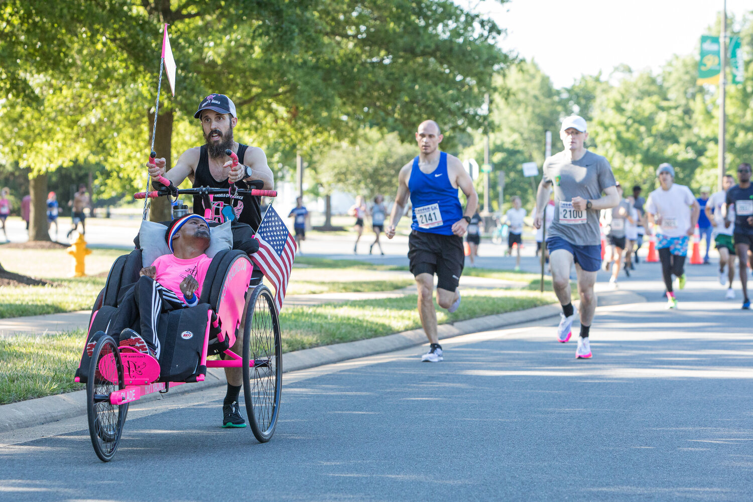 The runner helps a friend in a wheelchair participate in the race.