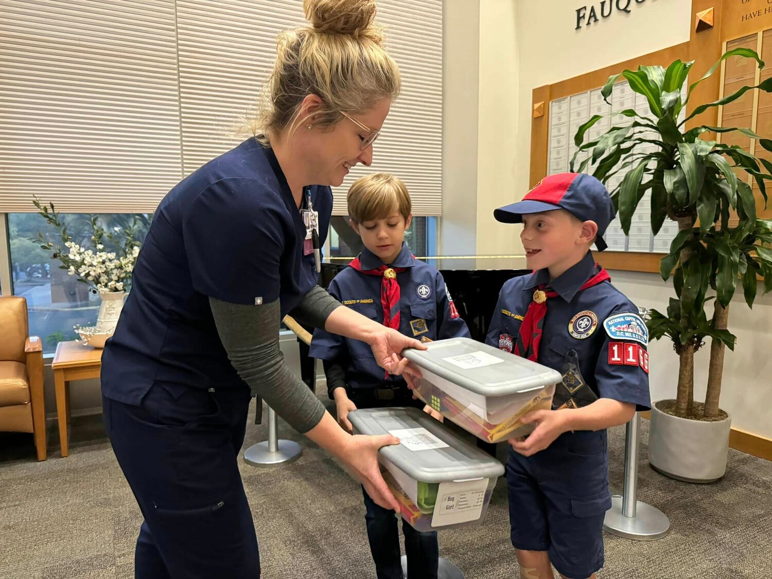 Cub Scouts hand boxes over to a nurse at Fauquier Hospital.