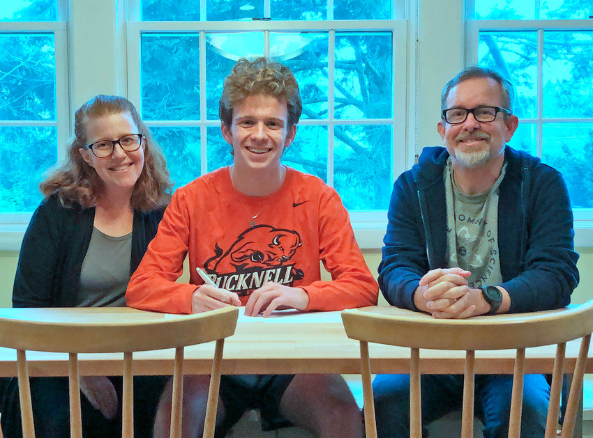 With his parents alongside him, Germantown Friends senior Bobby Lynam signs his National Letter of Intent to run cross country at Bucknell University.