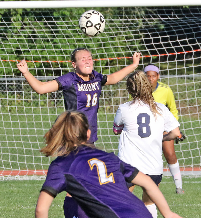 Mount senior Anna Shields heads away a ball served toward the 18-yard-line. In the foreground is freshman Meg Kelemick, and in the background is senior goalie Sam Ammons.