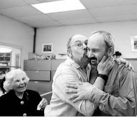 After learning that he won the Pulitzer Prize in 1998, Buddy Stein (right) is embraced and kissed by his brother, Richard, who is now a member of the Chestnut Hill Local Board, with their mother, Celia, beaming nearby.