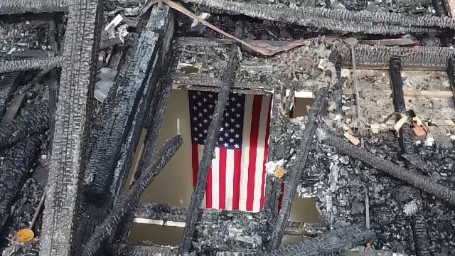 Photo of a school flag inside burned remains of Our Mother of Consolation School in Chestnut Hill. Photo by Jaxon Rosenblatt