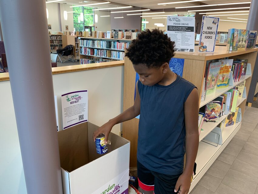 Preston Jamison, age 10, contributes to the Wyndmoor Library&rsquo;s food drive.