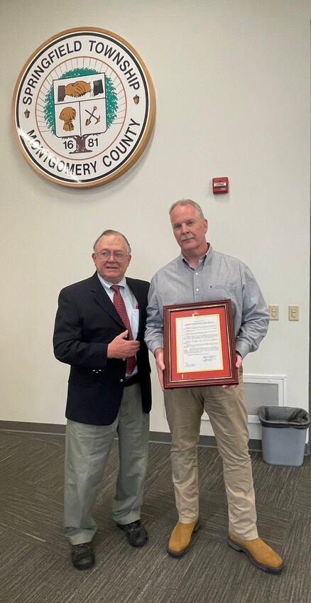 Commissioner Peter Wilson gives Springfield Township Police Officer Mark Hoisington the Board of Commissioners resolution honoring his 34 years of commendable public service.