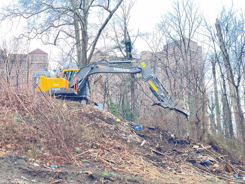City sanitation workers had to navigate a steep slope behind Valley Greene to get all the trash that had fallen along it.