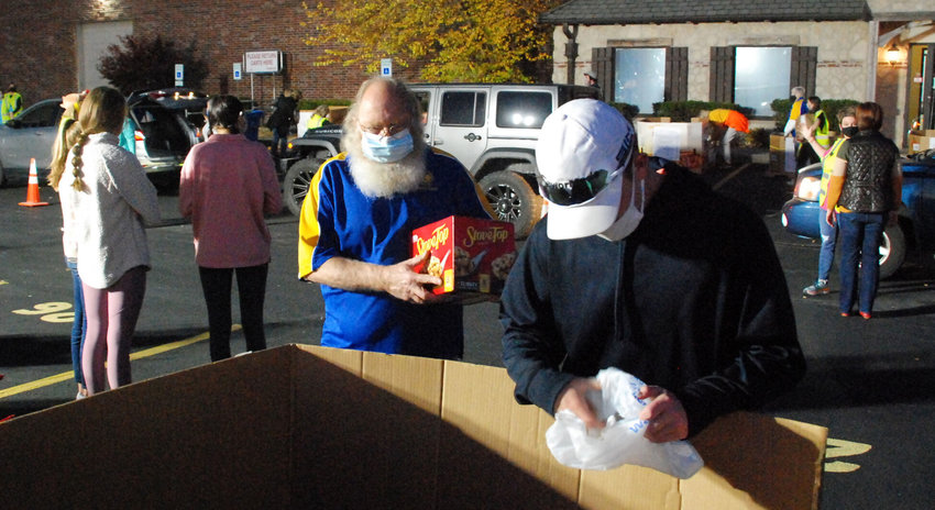 STEVE TALLAKSEN (center, in blue) volunteered in the parking lot at Least Of These food pantry in Ozark in preparation for Thanksgiving in 2020.