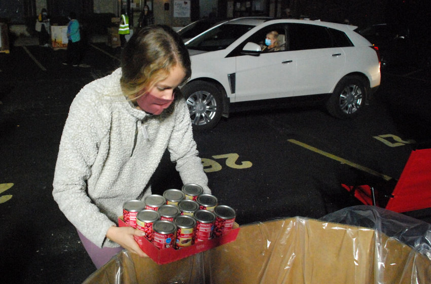 A LEAST OF THESE VOLUNTEER loads canned cranberry sauce into a donation bin in the parking lot at Least Of These food pantry off of James River Road in Ozark Nov. 5, 2020.