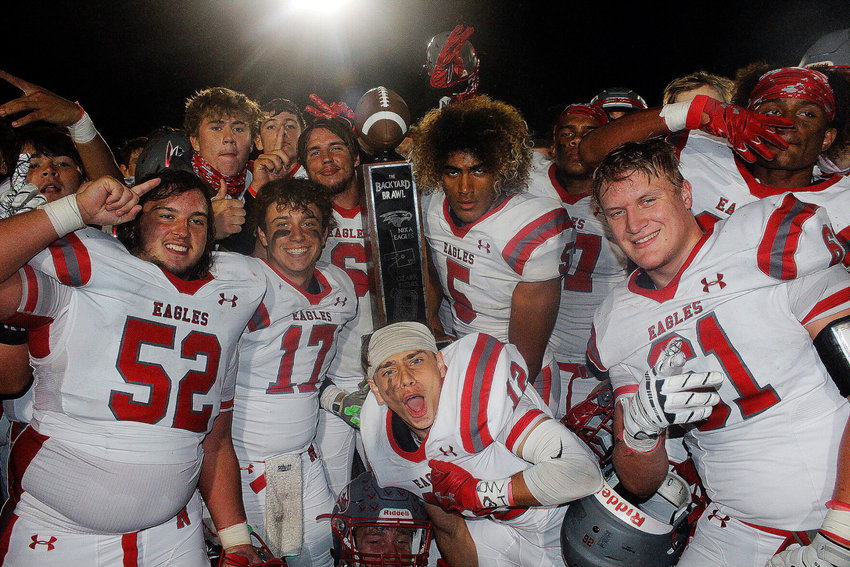 NIXA PLAYERS happily pose with the Backyard Brawl trophy after the Eagles beat Ozark 35-7 Friday.