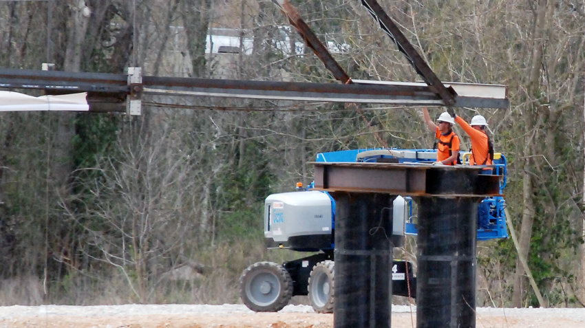 CONSTRUCTION WORKERS place a truss of the historic Riverside Bridge on its moorings across the Finley River on the Bass Pro Shops&rsquo; Finley Farms property.