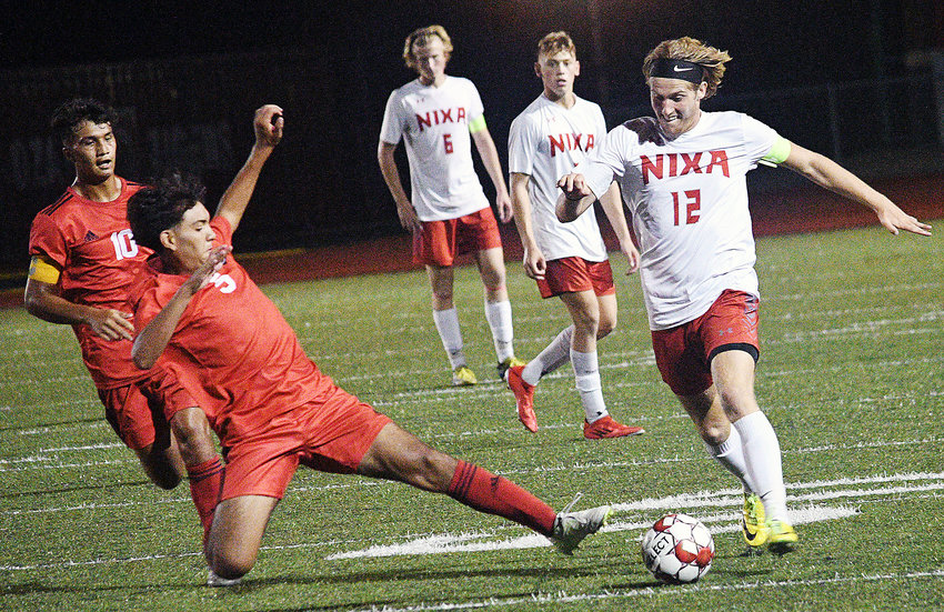 OZARK&rsquo;S ADRIAN ORTEGA hits the turf to try tip the ball away from Nixa&rsquo;s Landon Myers during the Tigers&rsquo; 3-2 double-overtime win Tuesday.