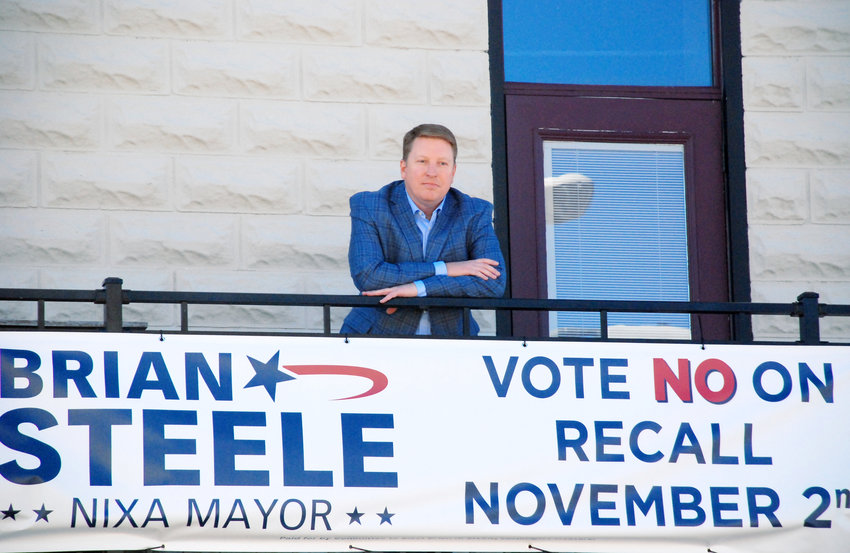 NIXA MAYOR BRIAN STEELE stands above a campaign sign on the upper level of the Main Event Center at the intersection of Main Street and Highway 14 in Nixa.