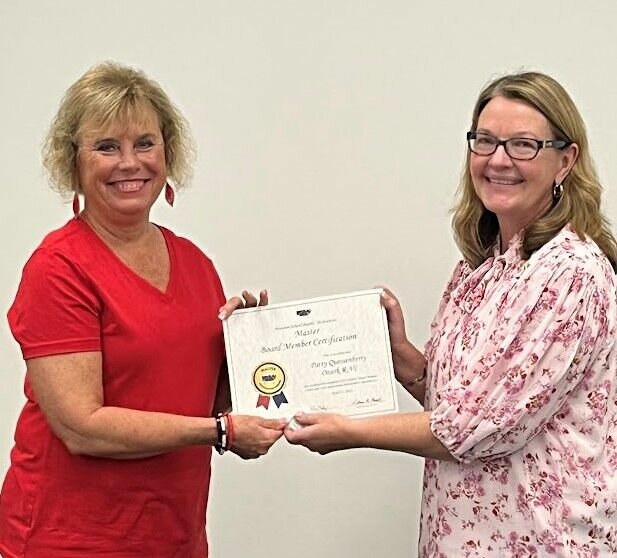 Ozark School Board President Sarah Adams Orr, right, presents Patty Quessenberry with her MSBA advanced and master certifications during a recent meeting.