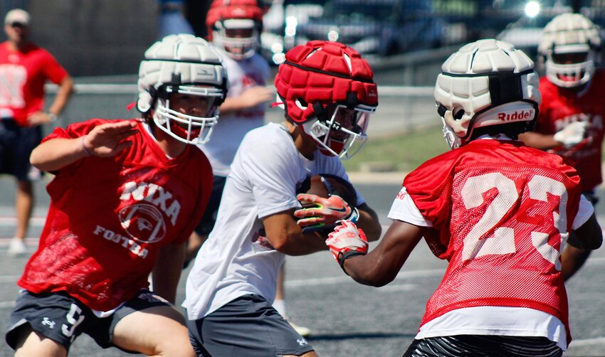 NIXA'S RYLAN MICHEL, center, carries the ball after a catch in between two defenders at an Eagles practice.