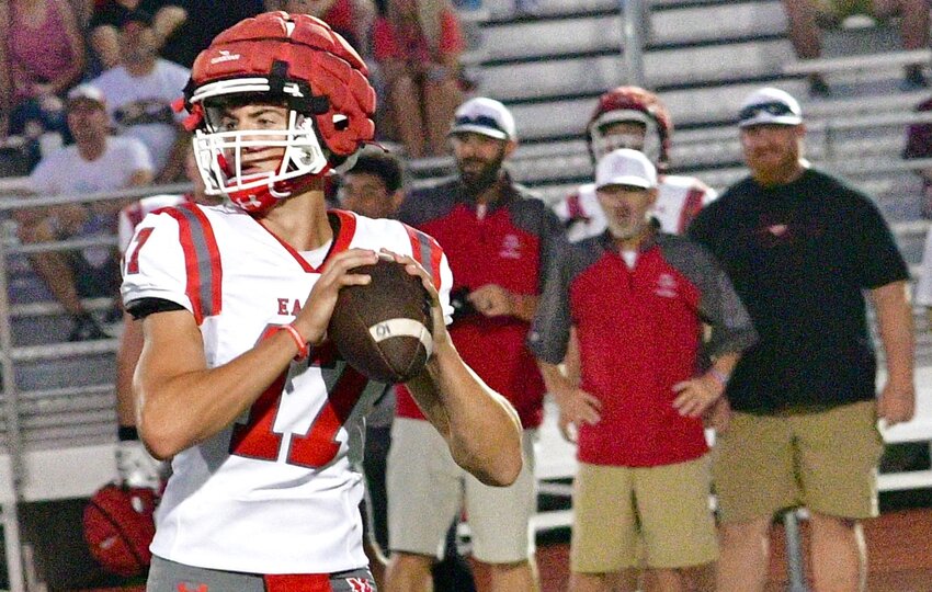 NIXA'S DREW BLEVINS eyes receivers downfield while under the watchful eyes of Eagles coaches.