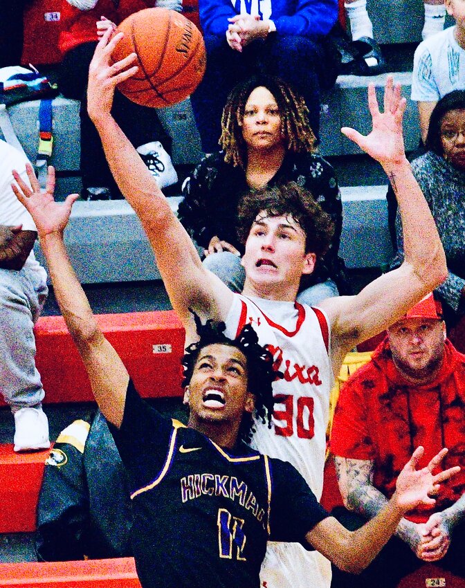 NIXA'S JOSH PETERS grabs a rebound over a Hickman player on Saturday.