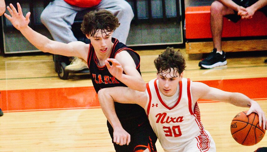 NIXA'S JOSH PETERS drives to the paint while defended by Ozark's Hudson Roberts on Friday.