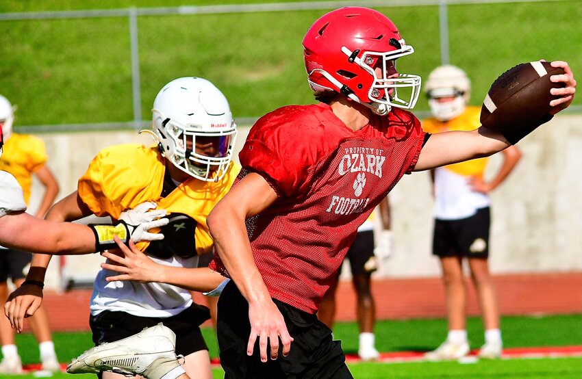 OZARK'S PEYTON RUSSELL holds the ball across the goal line while running for a touchdown in a practice with Kickapoo.