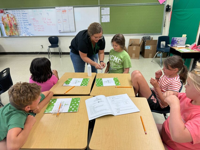 Ag Moves educator helps students water soybean germination necklaces.