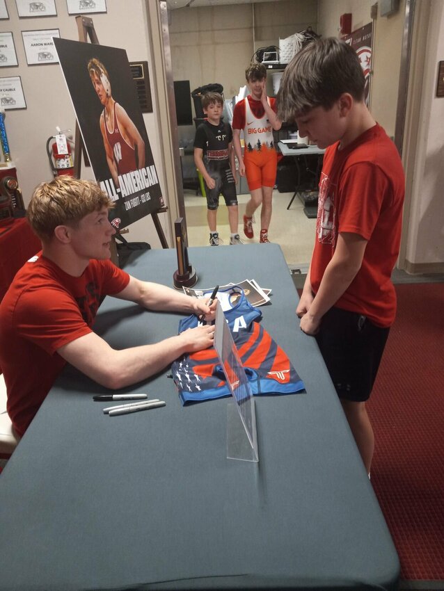 Zan Fugitt signs an autograph for Easton Peterson, 12, before the wrestling clinic, Photo by Steve Chapman.