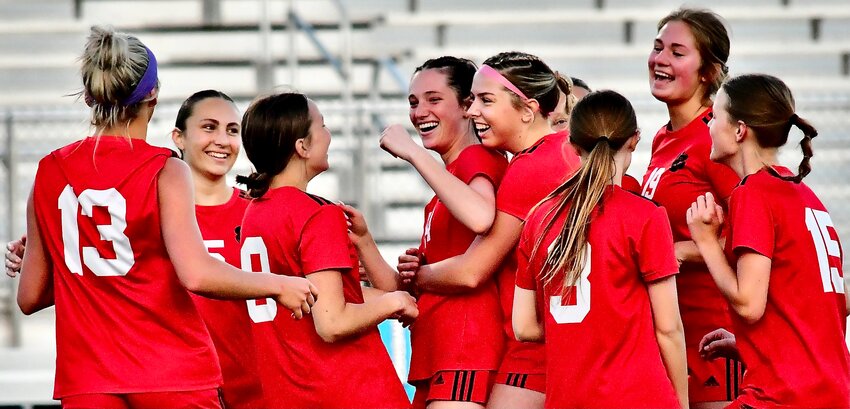 OZARK'S BROOKLYN SCHULTE is surrounded by teammates after scoring a goal.
