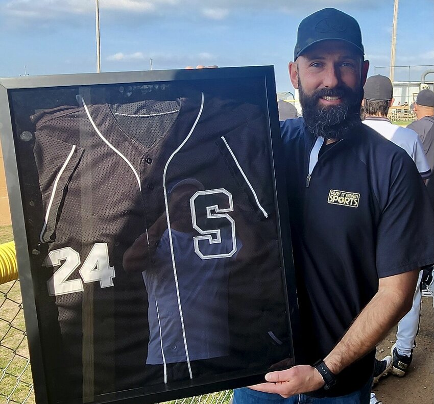 SPARTA GRAD BROCK KISSEE holds his retired uniform from his Trojans playing days.