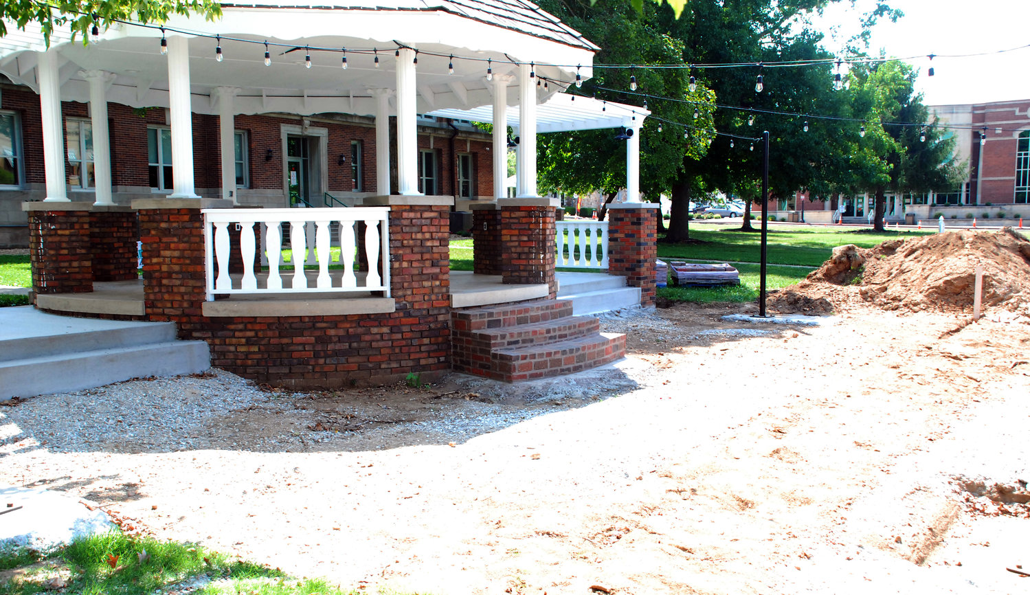 A NEW SIDEWALK is being built alongside the expanded gazebo on the west side of the Ozark square on North Second Street.