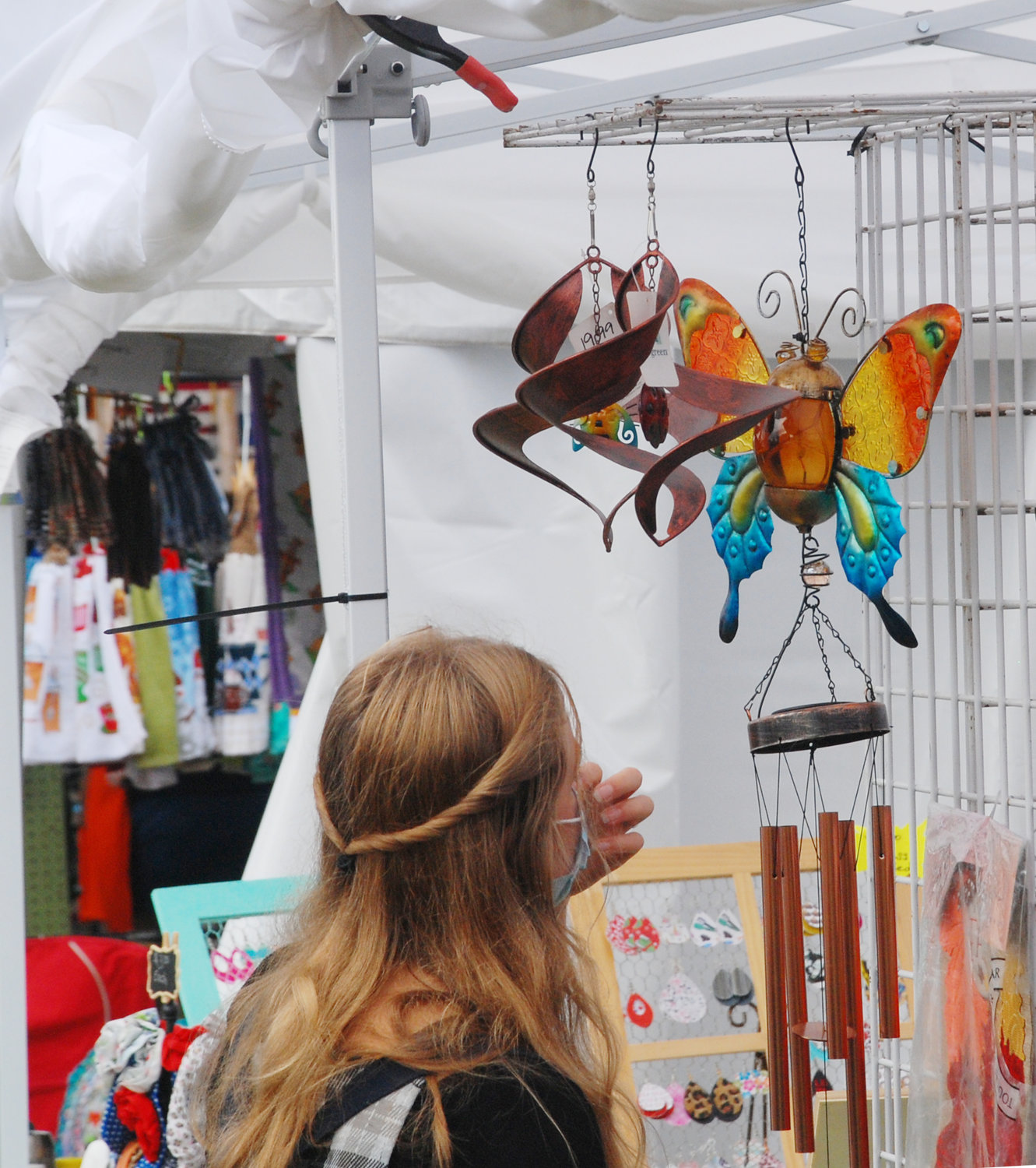 A WOMAN EXAMINES A HANGING DECORATION from one of the 300-plus vendor booths at Finley River Park. The Ozark Arts and Crafts Show kicked off Friday and ran through Sunday afternoon.