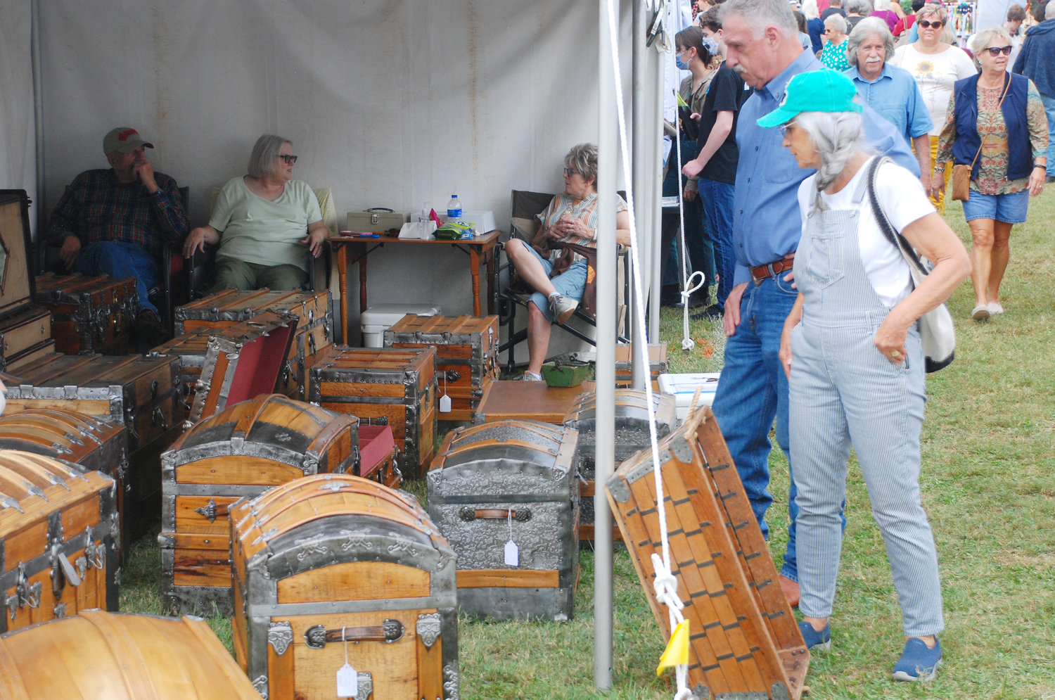 GUESTS EXAMINE HANDMADE WOODEN CHESTS for sale at the 47th Annual Ozark Arts and Crafts Fair at Finley River Park.