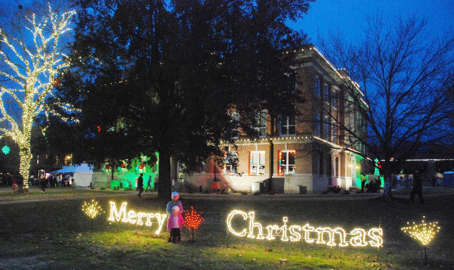 TWO GIRLS STAND ON THE SOUTH LAWN of the Christian County Historic Courthouse in Ozark as they await the start of the 56th annual Ozark Christmas Parade on Nov. 20.