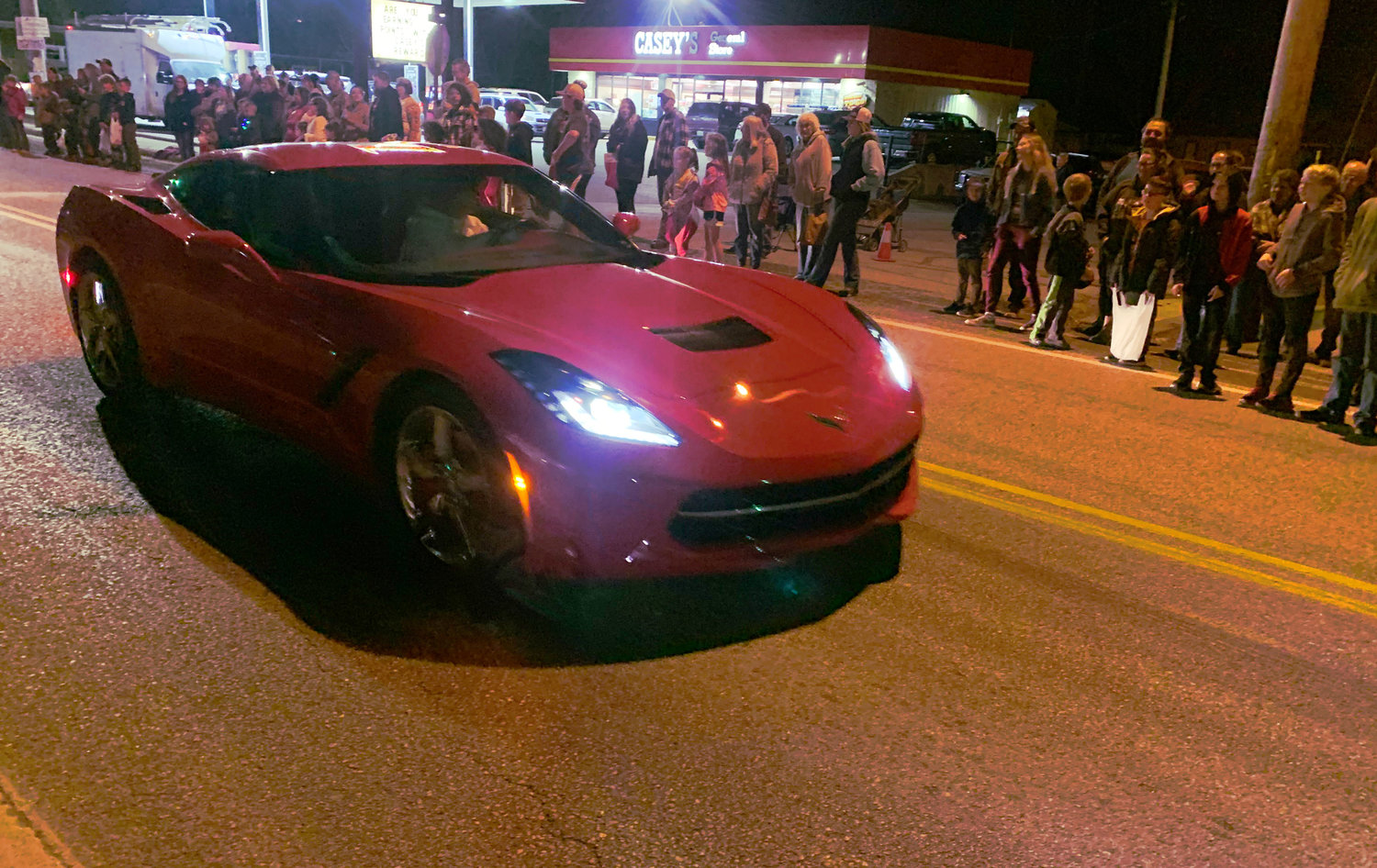 A LITTLE RED CORVETTE rolls east on Main Street in Sparta as people line the street to watch.