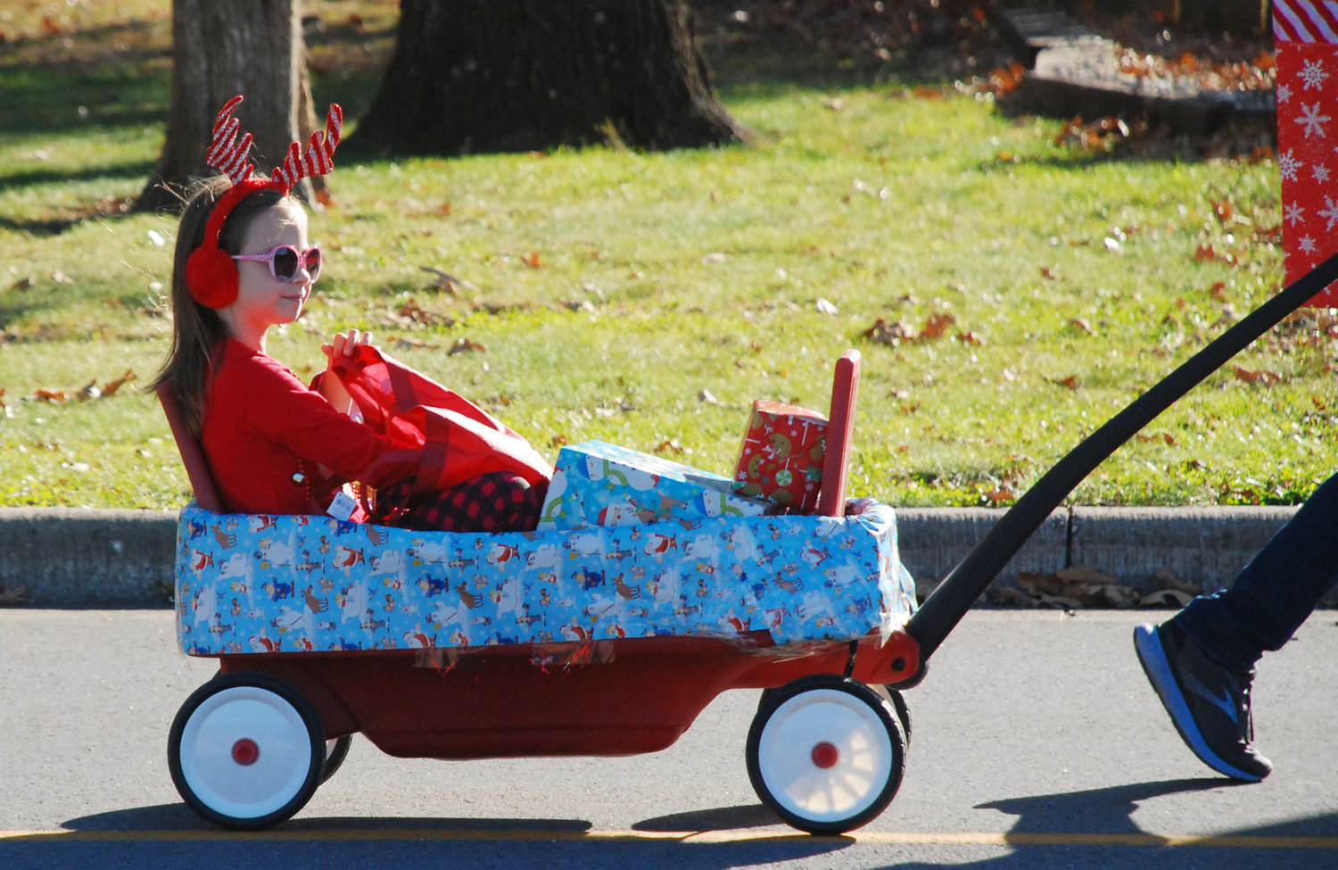 HITCHING A RIDE — A girl rides along in a wagon on a sunny December day.