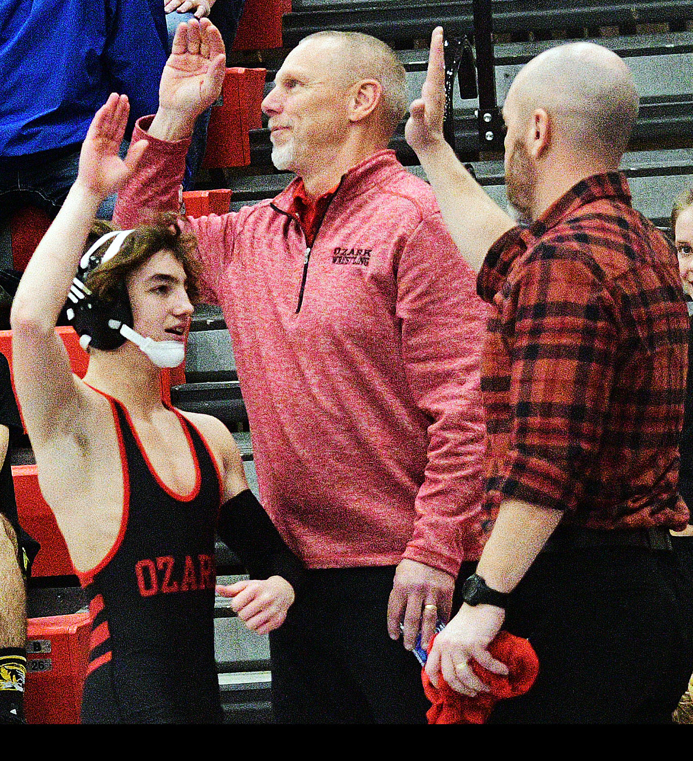 OZARK’S DAMIEN MOSELEY exchanges a high-five with Ozark coaches after winning a 106-pound District championship.