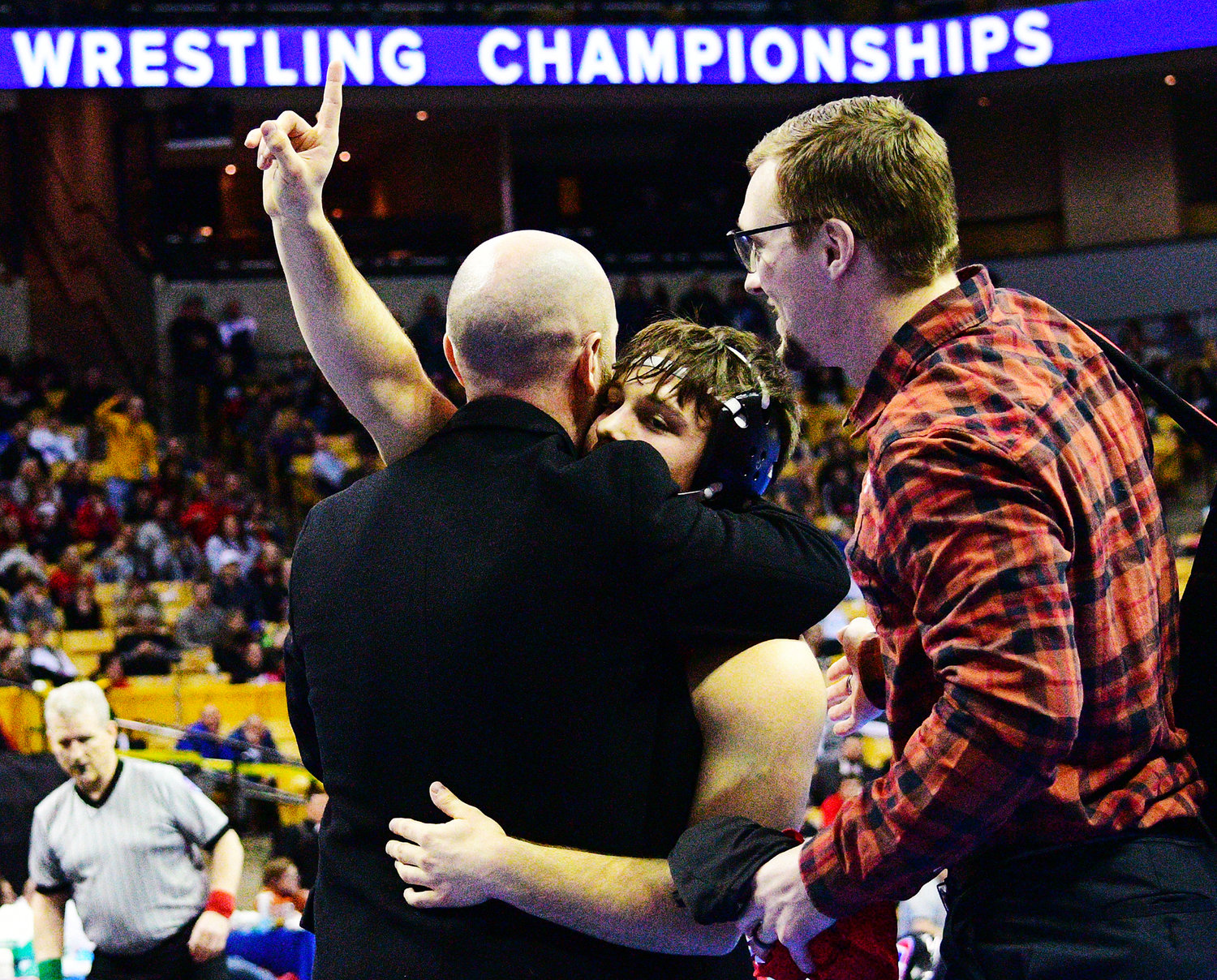 OZARK’S BRAXTON STRICK shares a hug with Tigers coach Tod Sundlie after winning the Class 4 152-pound championship at the State Wrestling Tournament on Saturday.