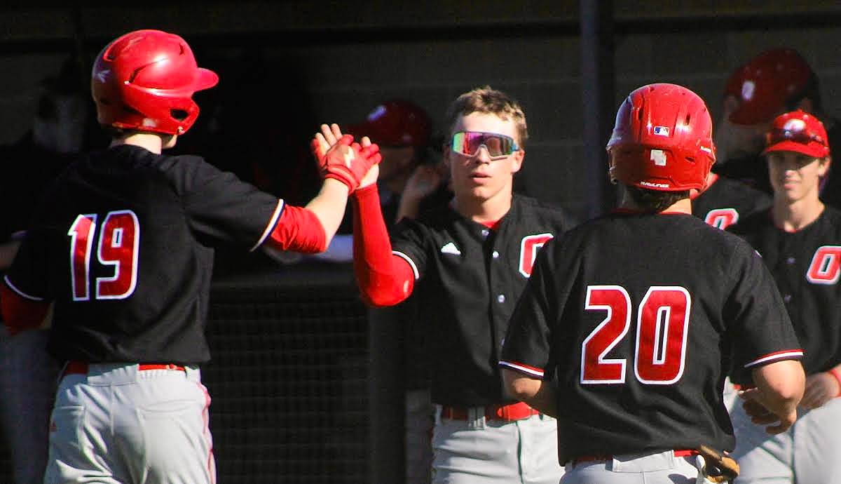OZARK'S DEVYN WRIGHT AND GAGE DEPEE are greeted by Rhett Hayward after scoring runs at Republic on Tuesday.