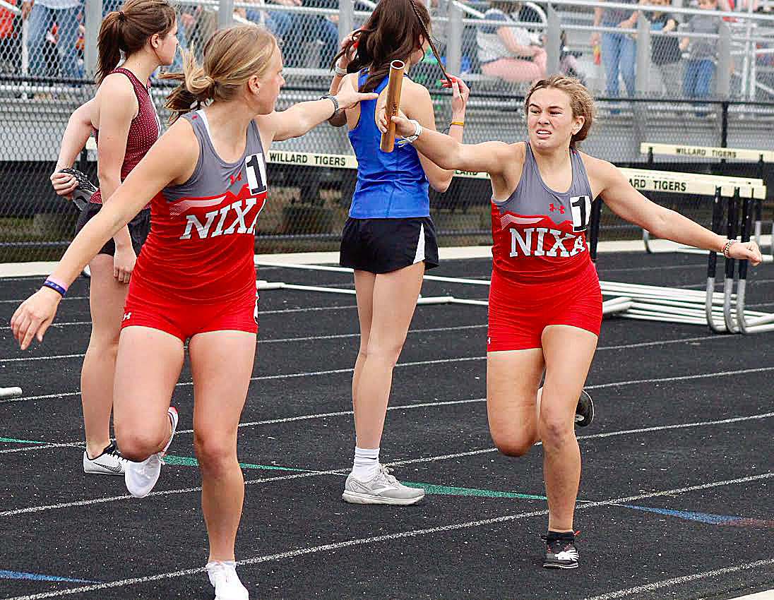 NIXA’S RYLEE SEXTON AND EMILY HARRIS complete a hand-off in the 4 x 800 relay at Willard’s Jason Pyrah Invite last week.