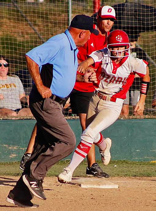 OZARK'S KELSIE BATEY rounds first base only to have the infield umpire in her path.