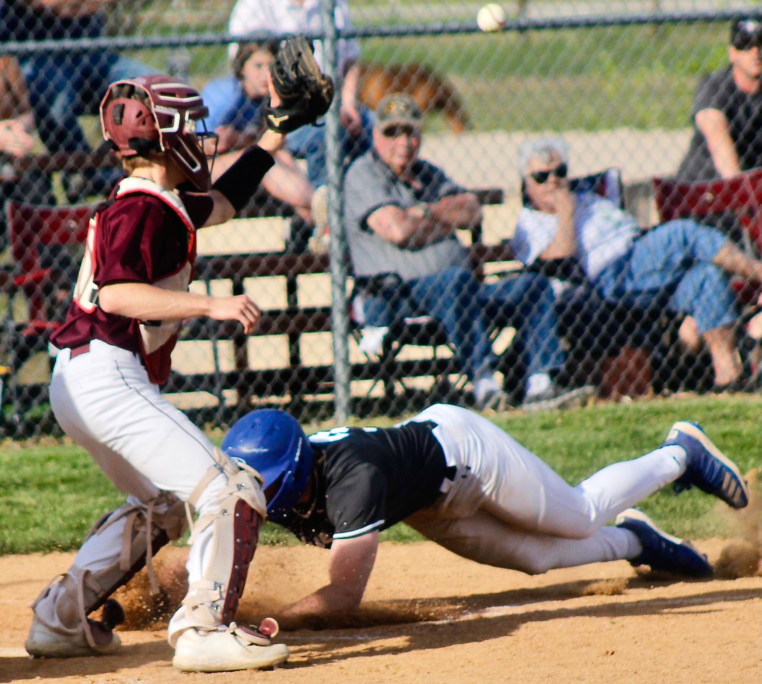 CLEVER'S TRACE BARNES slides safely across home plate as Spokane catcher Jace Leigh catches a late throw.