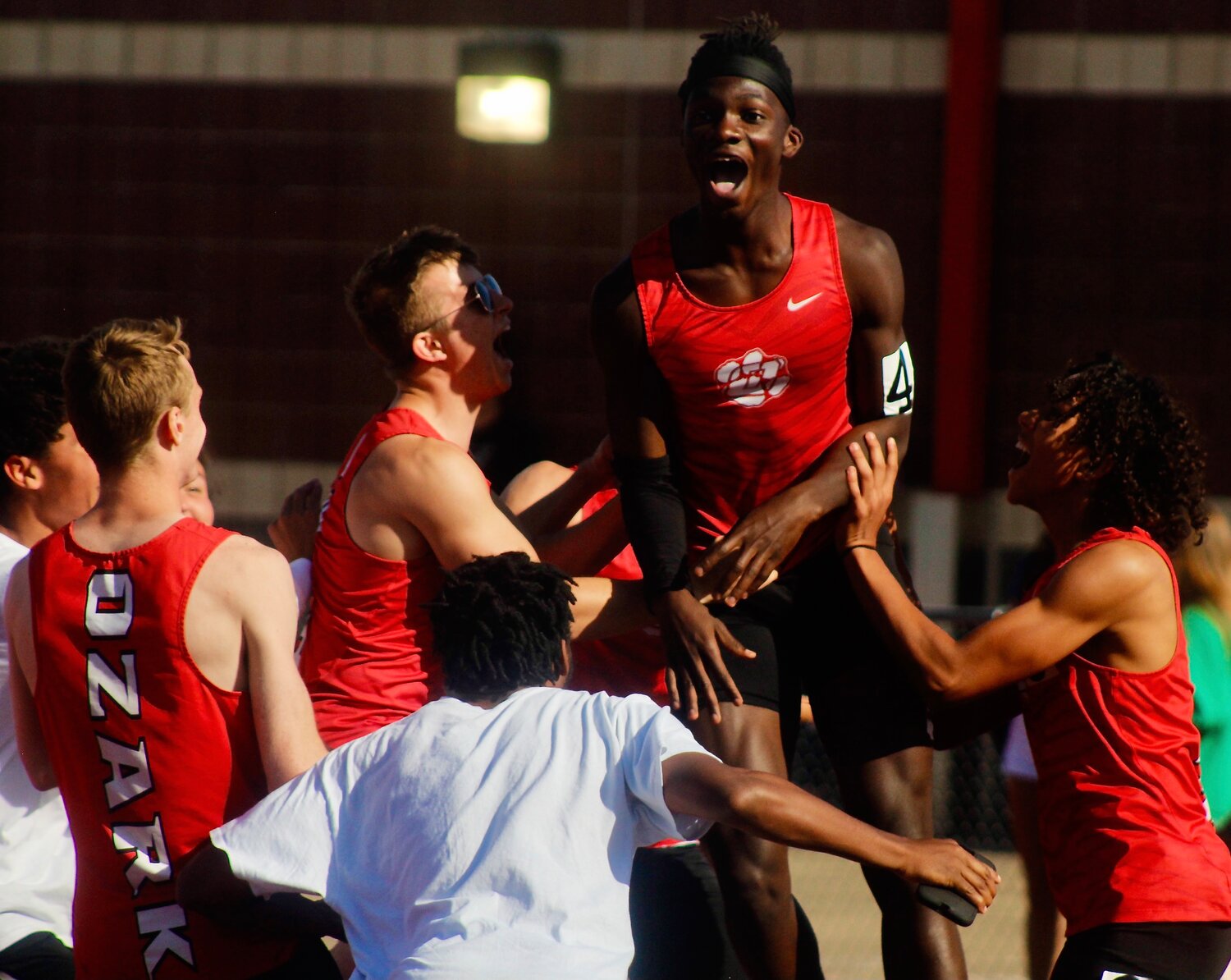 OZARK'S MAMADY EMBOLA celebrates his win in the 110 hurdles with teammates at the COC Meet on Wednesday.