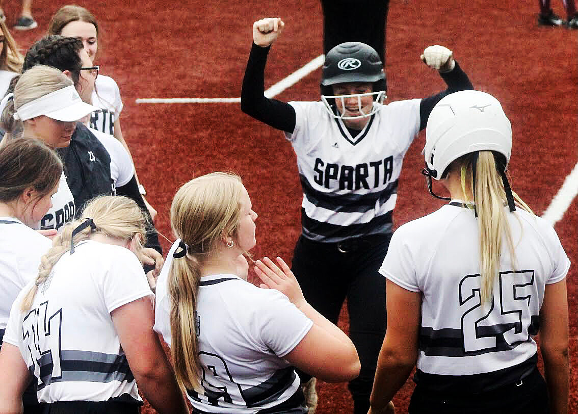 SPARTA'S MYA FULTON is met by teammates while scoring on a home run by Megan Brown Friday.