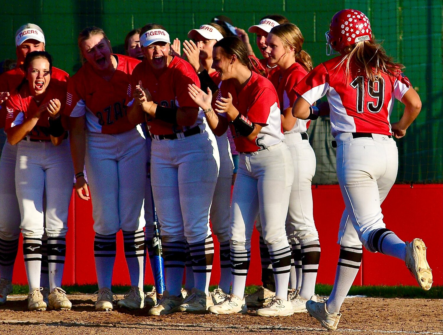 OZARK'S AUDREY CARLTON is met by teammates after hitting a grand slam.