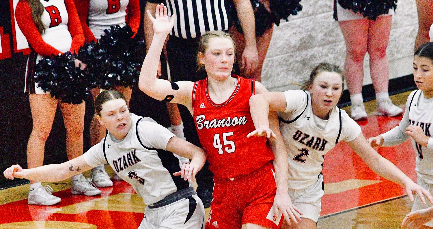 OZARK'S KAYLEE LINNEBUR AND JOSIE ROBERTS defend a Branson player in the teams' matchup Monday.
