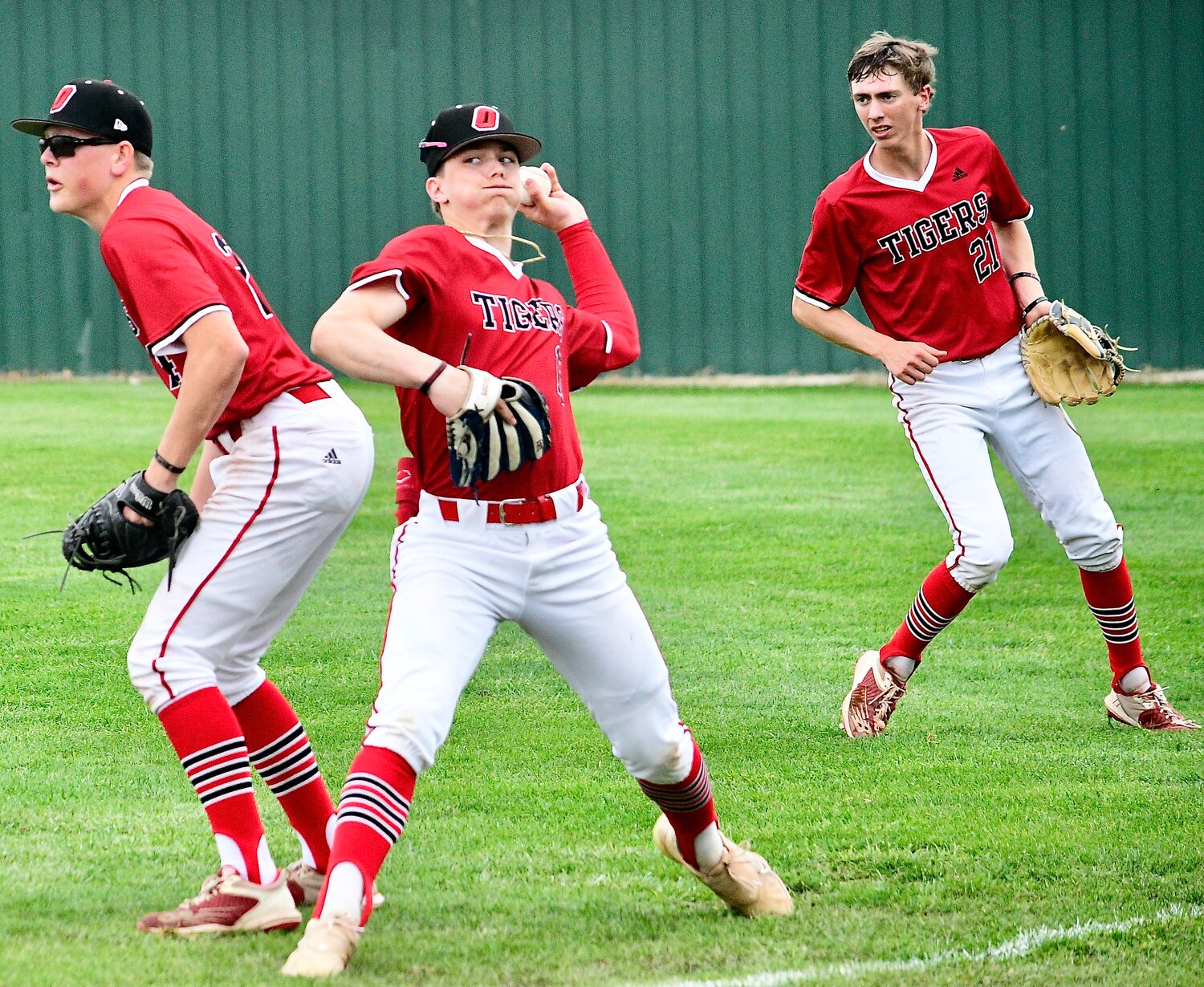 OZARK'S RYLAN SUTTON prepares to return the ball to the infield in between teammates Truman Griessel and Alex Nimmo.