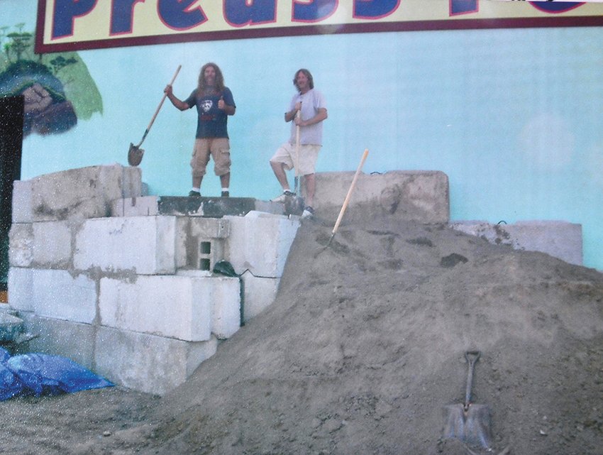 Rob Preuss (left) and Mike Wendt pause while constructing the waterfall feature in front of Preuss Pets in Old Town.