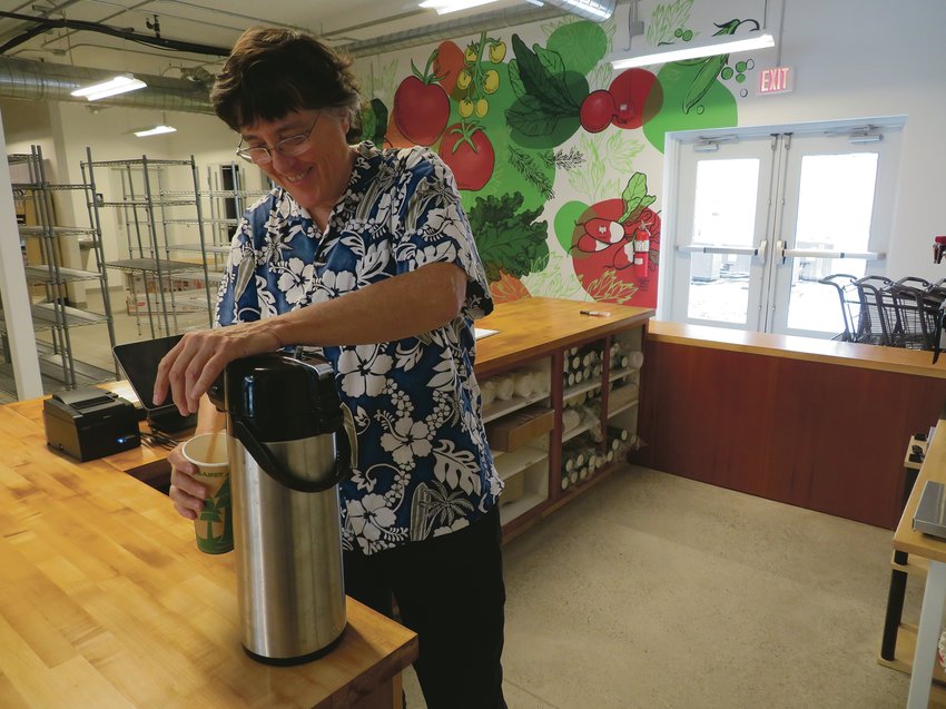 Sally Potter, general manager of Eastside Lansing Food Co-op, pulls a cup of coffee before meeting with her staff last week. The
wooden counter was formerly the jewelry counter at Mackerel Sky gifts in East Lansing. In the background is a mural by artist Kate Schneider, who lives a few blocks away.